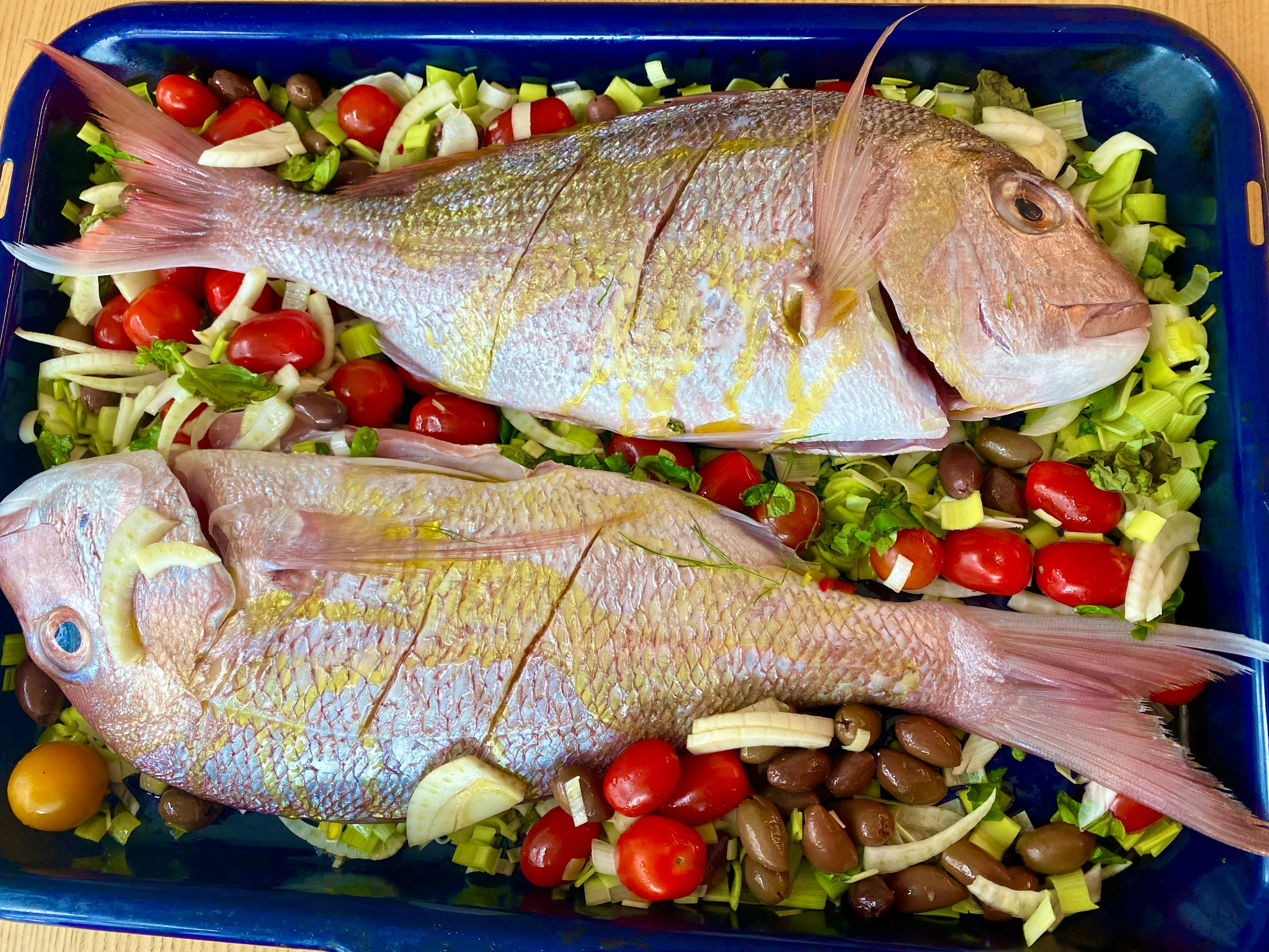 2 snappers on a bed of little tomatoes, olives and fennel