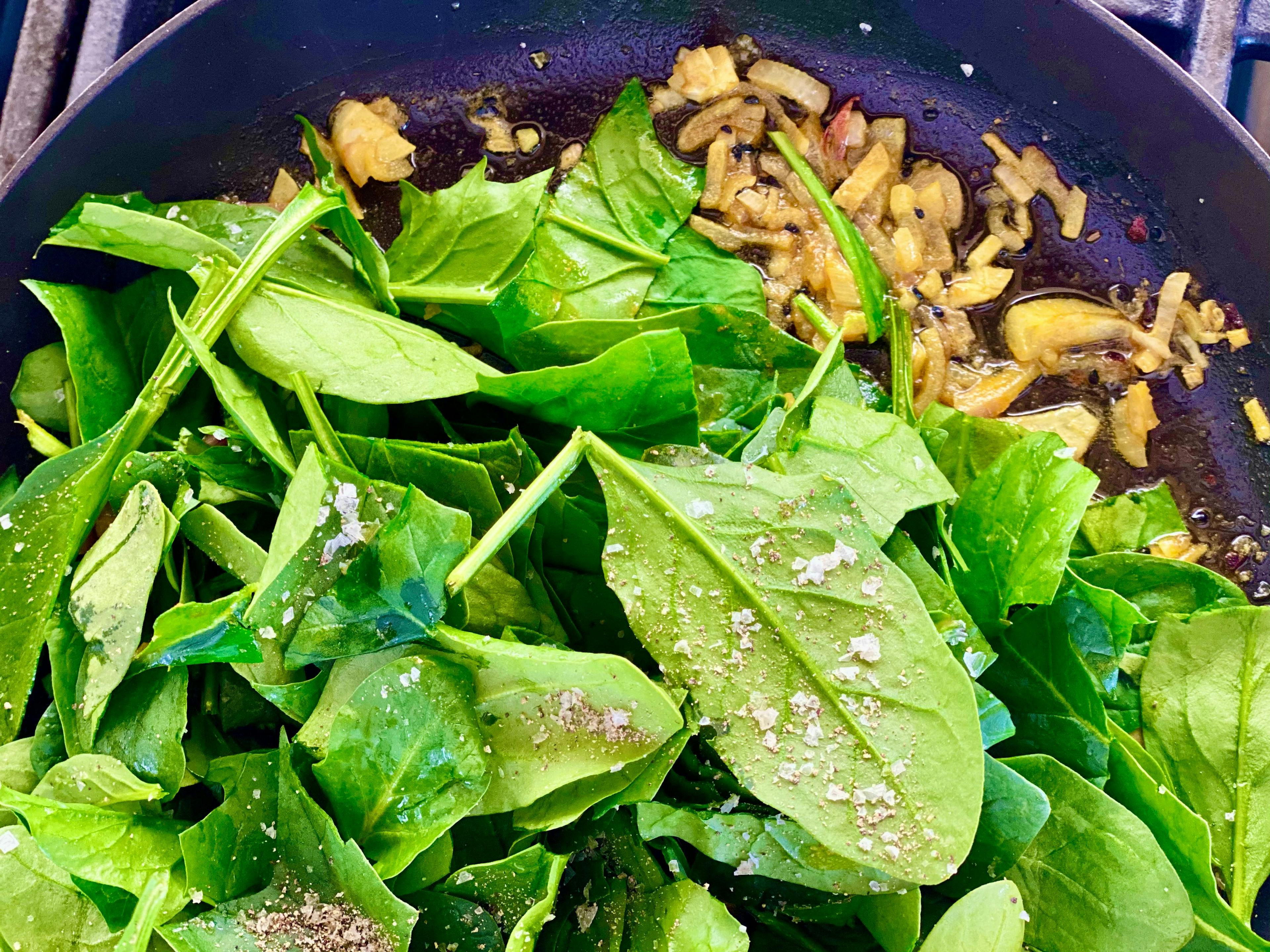 fresh spinach in frypan with onions