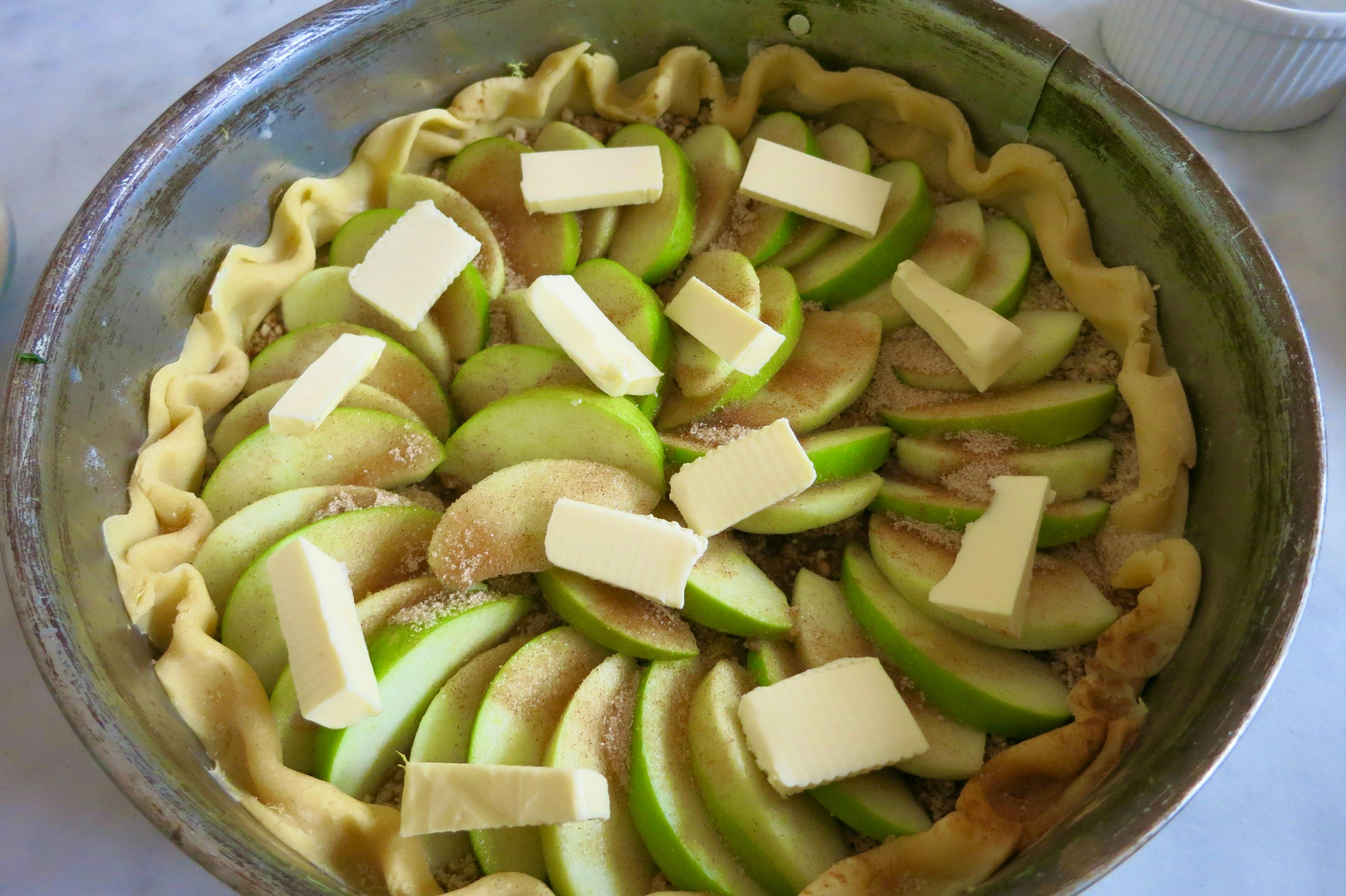 raw pastry with apples and butter pieces 