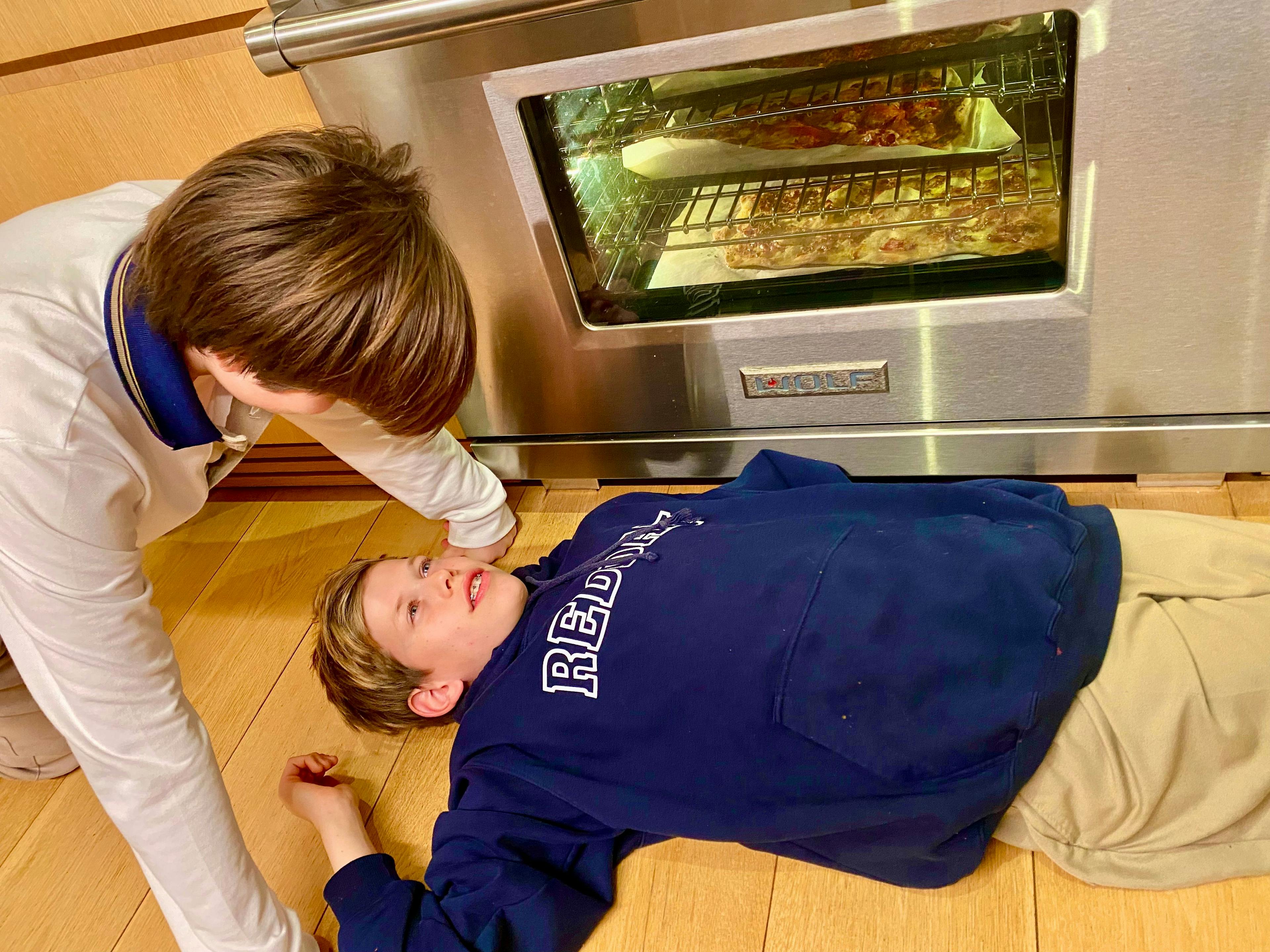 boys lying in front of oven