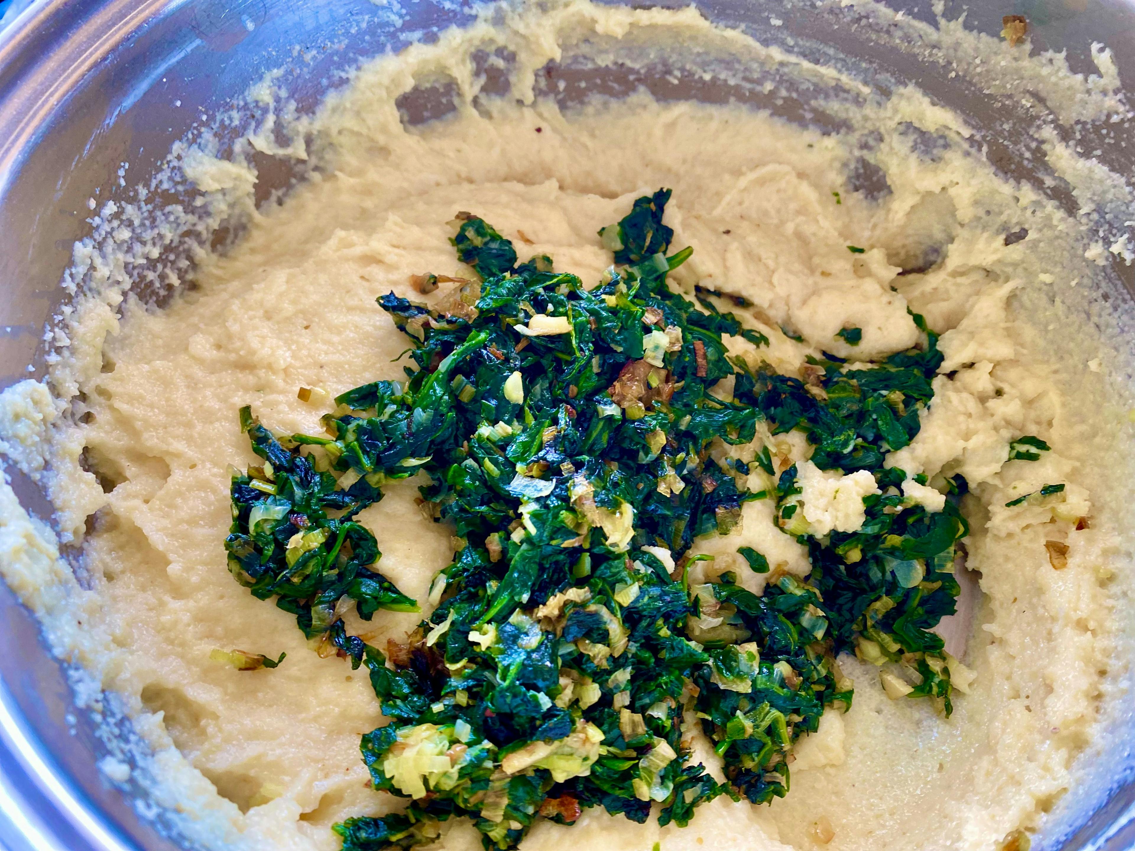 chopped spinach and leek being added to semolina purée