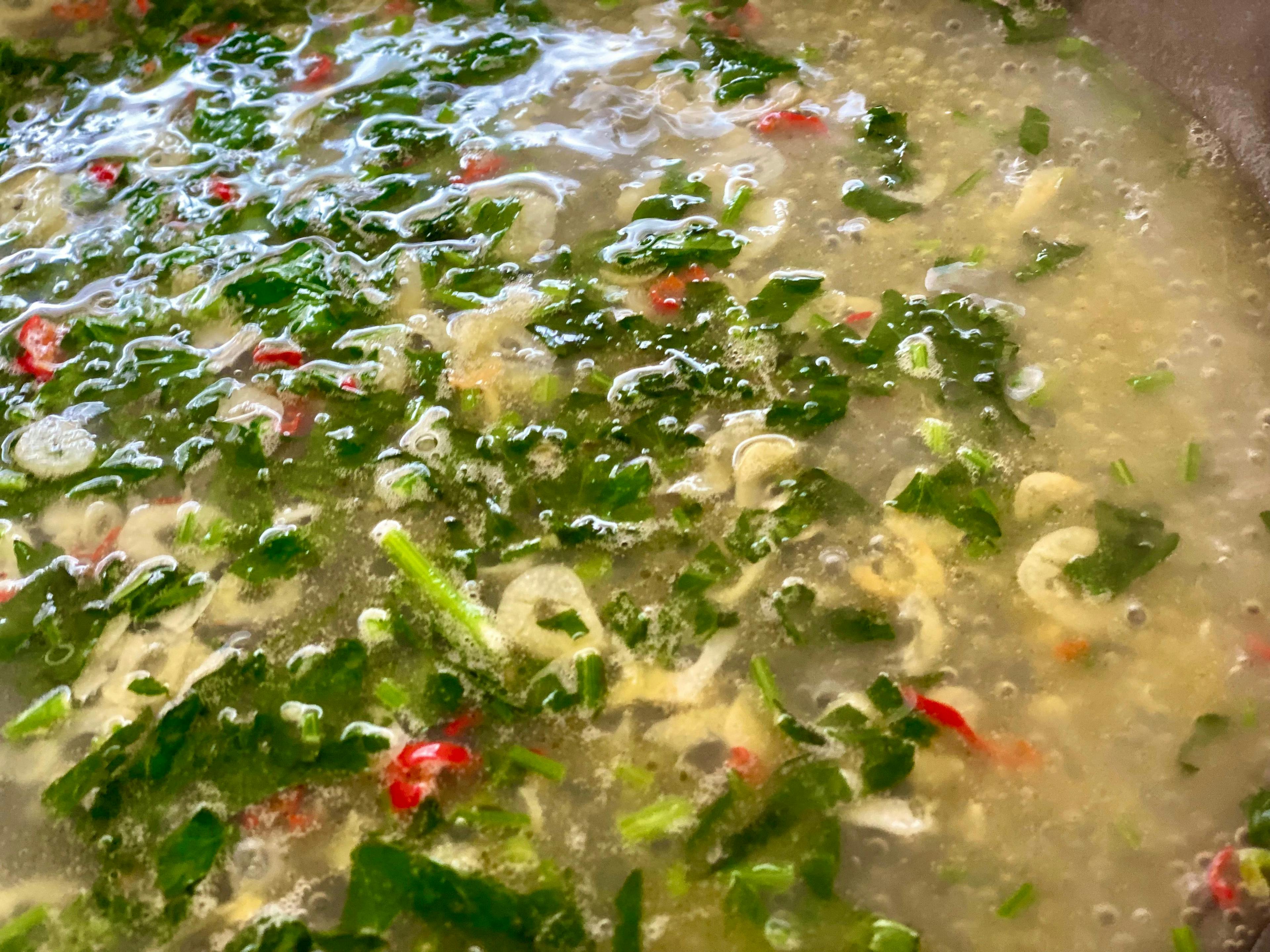 liquid simmering in pan with garlic, parsley and chillies