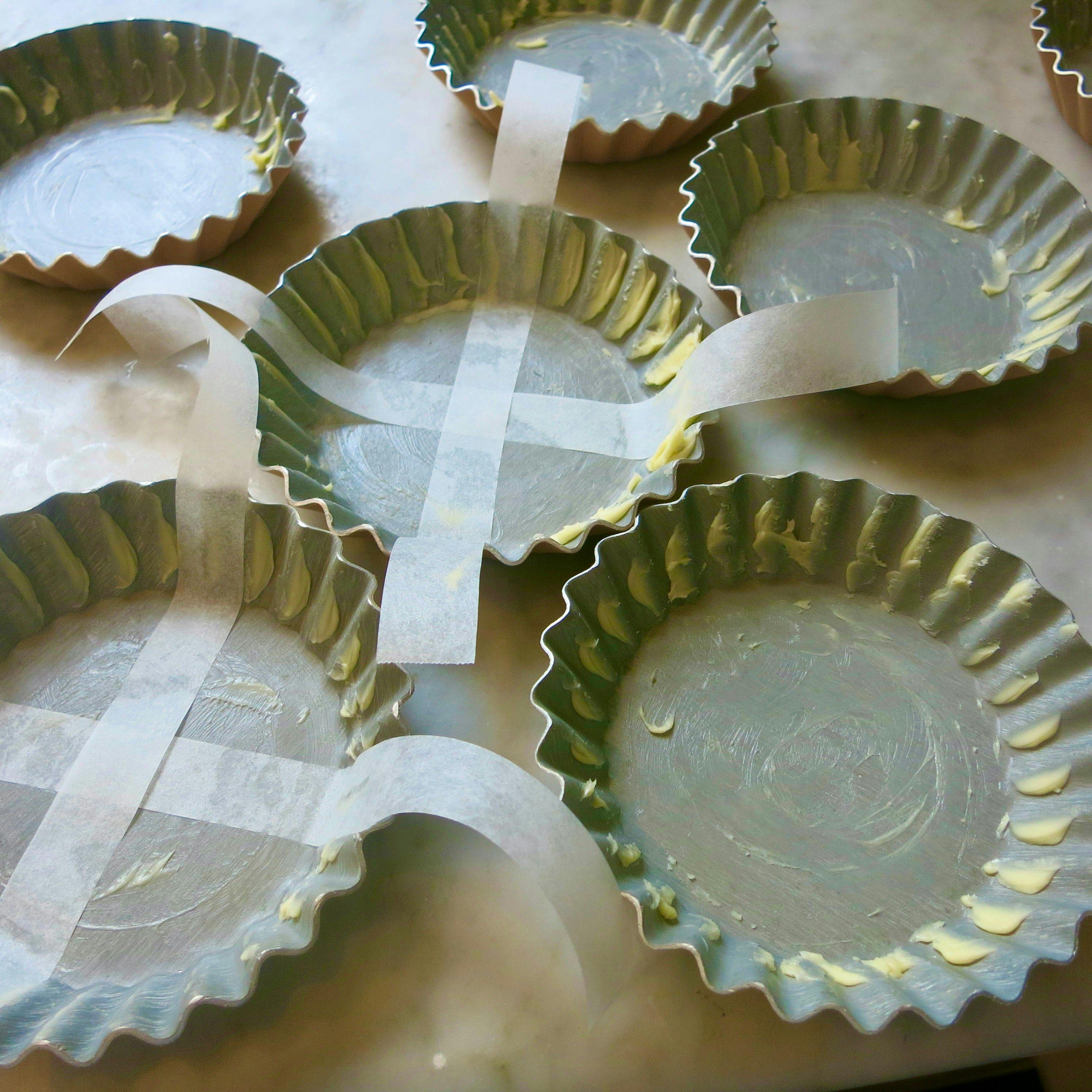 buttered pie dishes with grease proof paper strips across the base